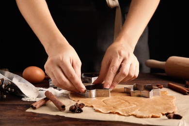 Photo of Woman making Christmas cookies at wooden table, closeup