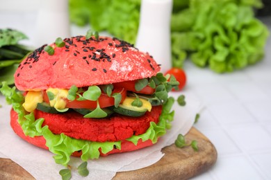 Photo of Tasty pink vegan burger with vegetables, patty and microgreens on white tiled table, closeup. Space for text