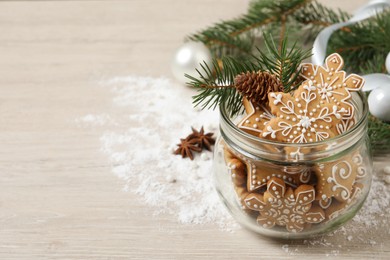 Photo of Tasty Christmas cookies in glass jar and festive decor on beige wooden table. Space for text