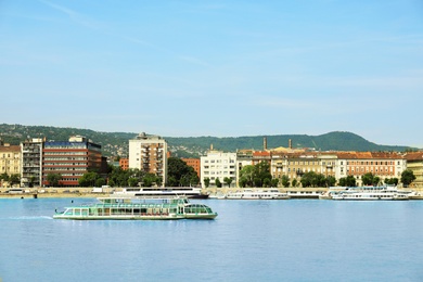 Photo of BUDAPEST, HUNGARY - JUNE 18, 2019: Beautiful view of Novotel and tour boat on Danube river