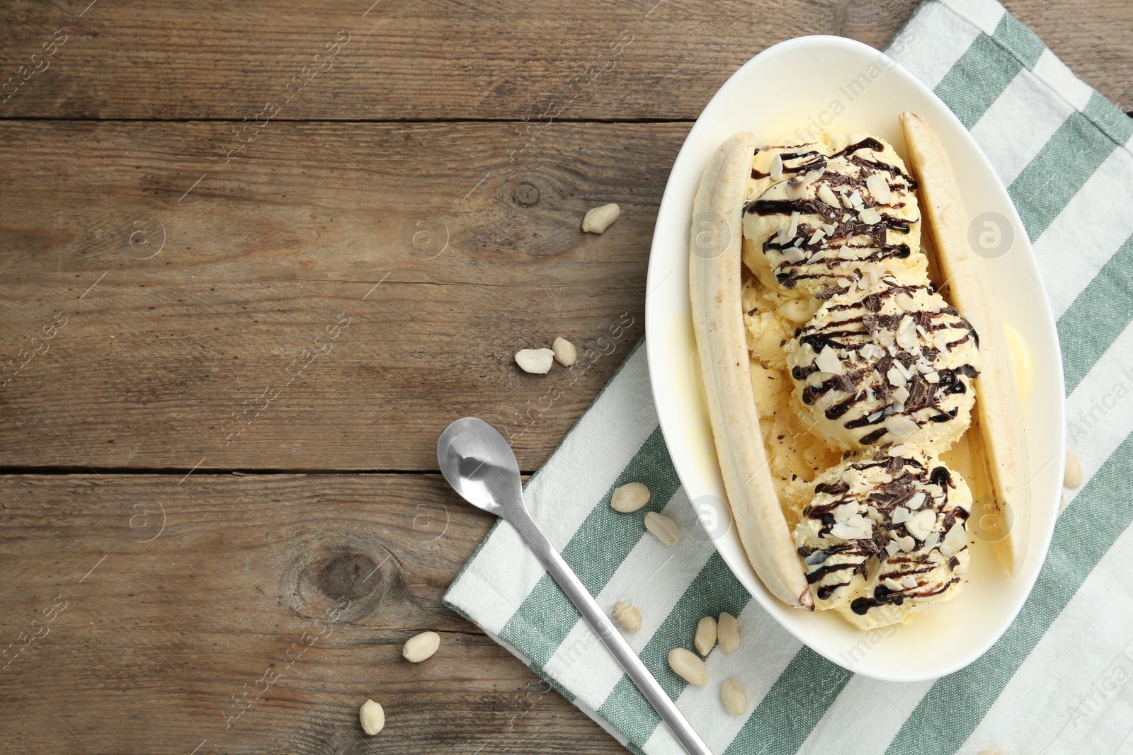 Photo of Delicious banana split ice cream on wooden table, flat lay. Space for text