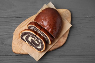 Photo of Cut poppy seed roll on grey wooden table, top view. Tasty cake
