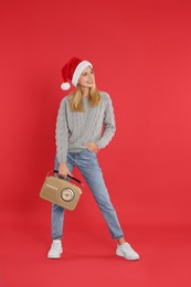 Photo of Happy woman with vintage radio on red background. Christmas music