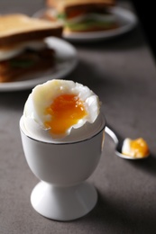 Photo of Soft boiled egg served for breakfast on grey table, closeup