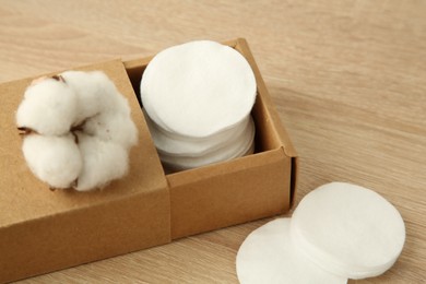 Photo of Cotton pads and flower on wooden table, closeup