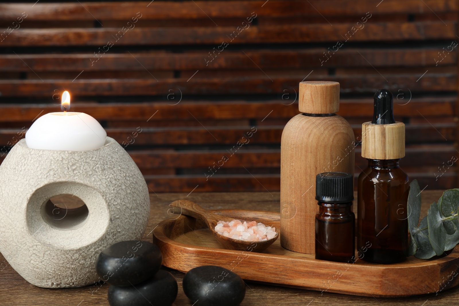 Photo of Different aromatherapy products and burning candle on wooden table