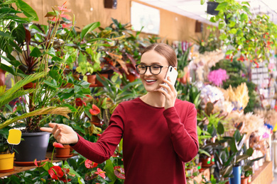 Photo of Female business owner talking on mobile phone in flower shop