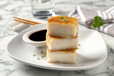 Photo of Plate with turnip cake on white marble table