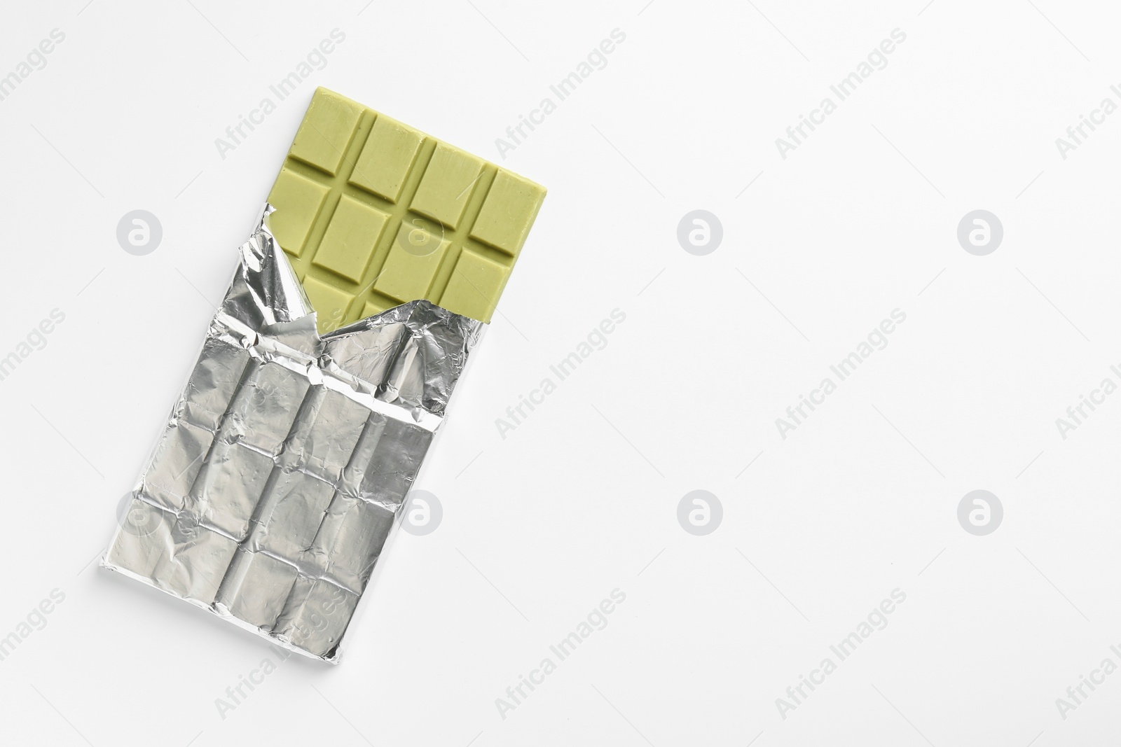Photo of Tasty matcha chocolate bar wrapped in foil on white background, top view. Space for text