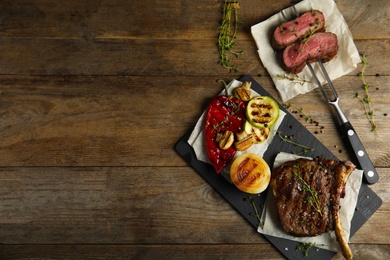 Flat lay composition with grilled meat on wooden table. Space for text