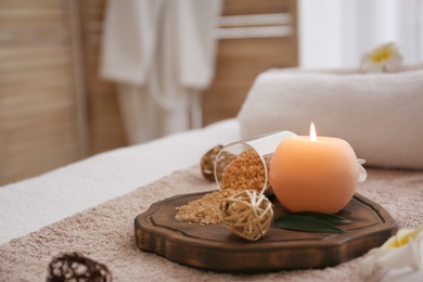 Photo of Burning candle and sea salt on massage table in spa salon, closeup