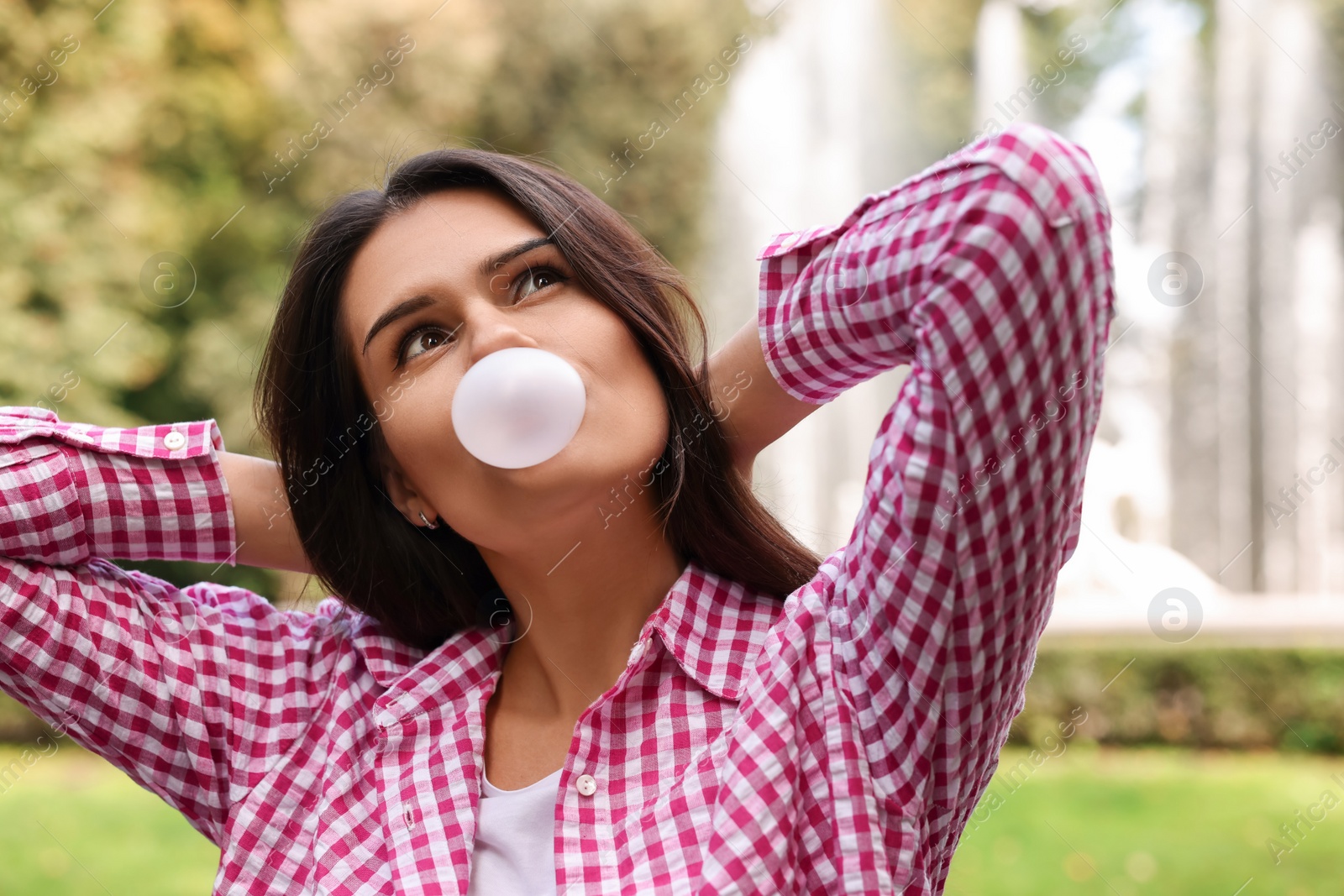 Photo of Beautiful young woman blowing chewing gum outdoors