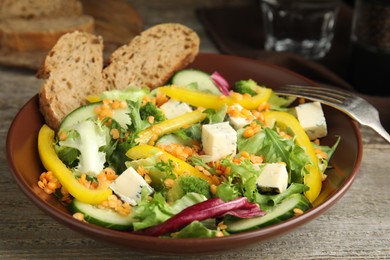 Photo of Delicious salad with lentils, vegetables and cheese on wooden table, closeup