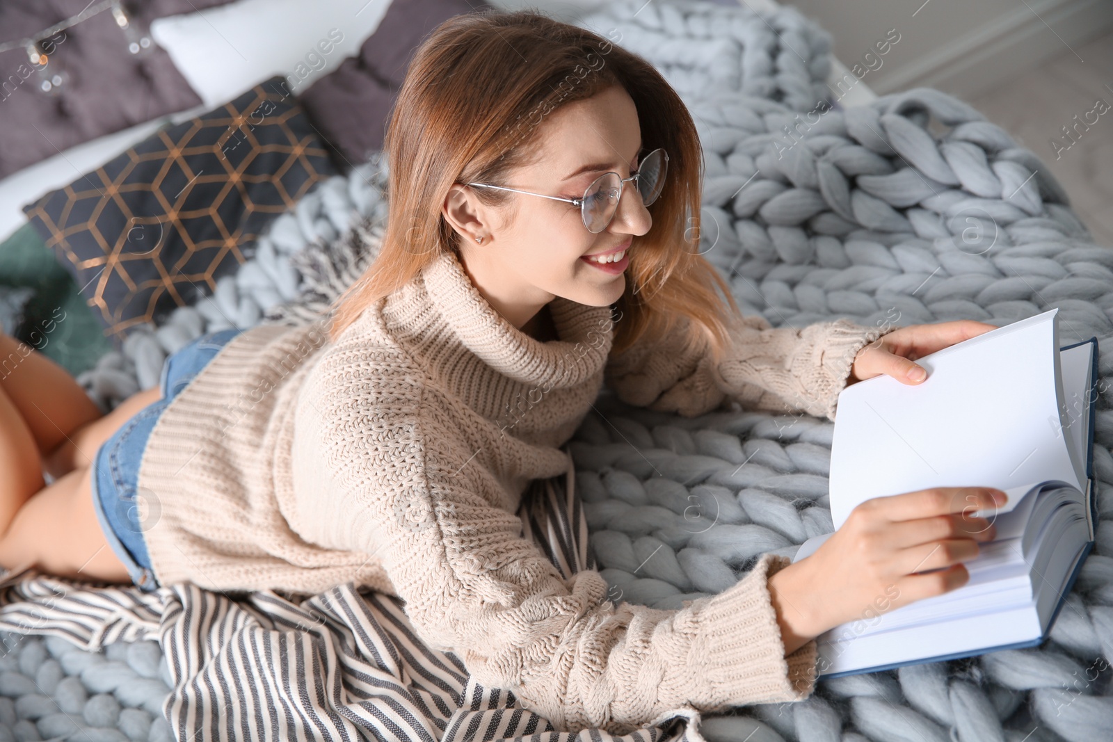 Photo of Young woman reading book on bed at home