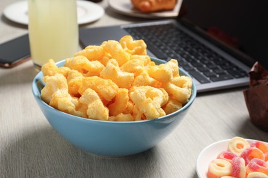 Photo of Bad eating habits at workplace. Tasty crispy snack in bowl on wooden table, closeup