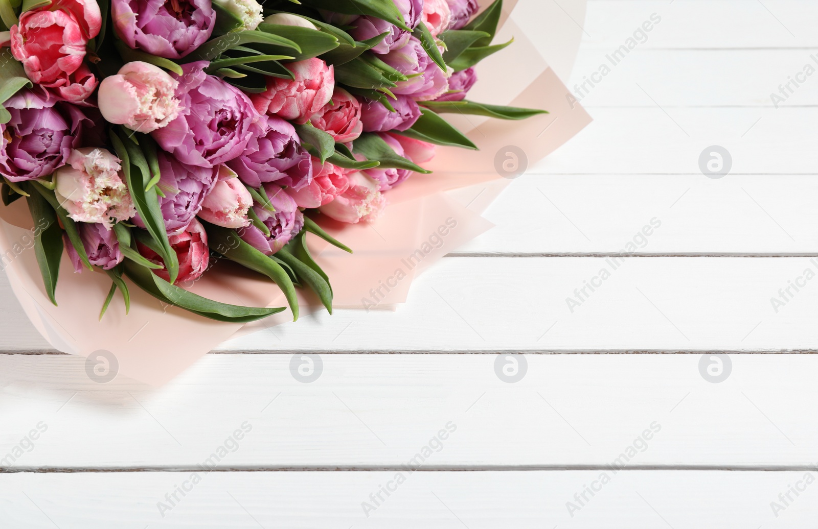 Photo of Bouquet of beautiful tulips on white wooden table, closeup. Space for text