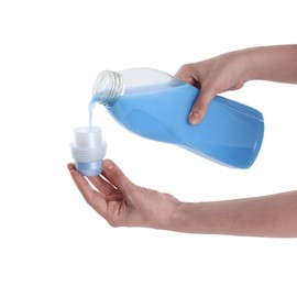 Photo of Woman pouring fabric softener from bottle into cap on white background, closeup