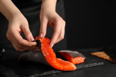 Photo of Chef removing scales from salmon for sushi at dark table, closeup