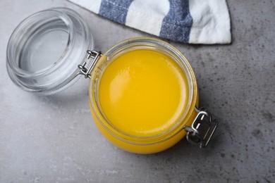 Photo of Glass jar of Ghee butter on grey table, top view