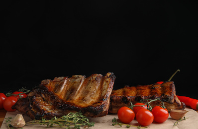 Photo of Tasty grilled ribs with tomatoes on table