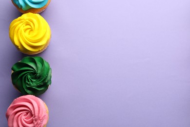 Photo of Delicious cupcakes with bright cream on violet background, flat lay. Space for text