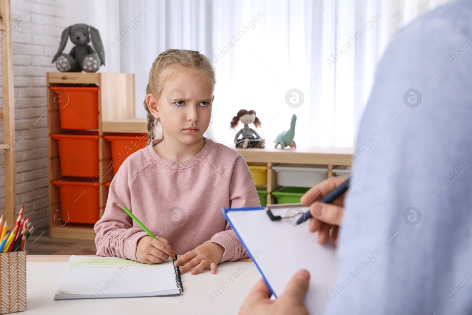 Photo of Little girl on appointment with child psychotherapist indoors