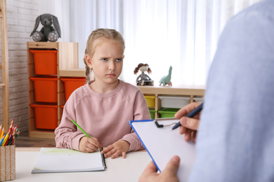 Photo of Little girl on appointment with child psychotherapist indoors