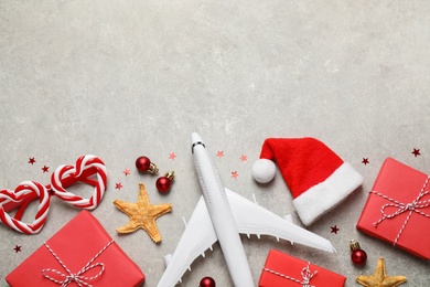 Photo of Flat lay composition with Christmas decorations and toy airplane on light table, space for text. Winter vacation