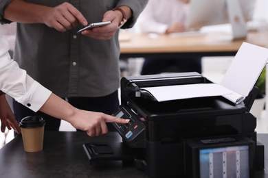 Employees using modern printer in office, closeup