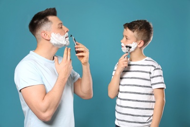 Photo of Dad shaving and son imitating him on blue background