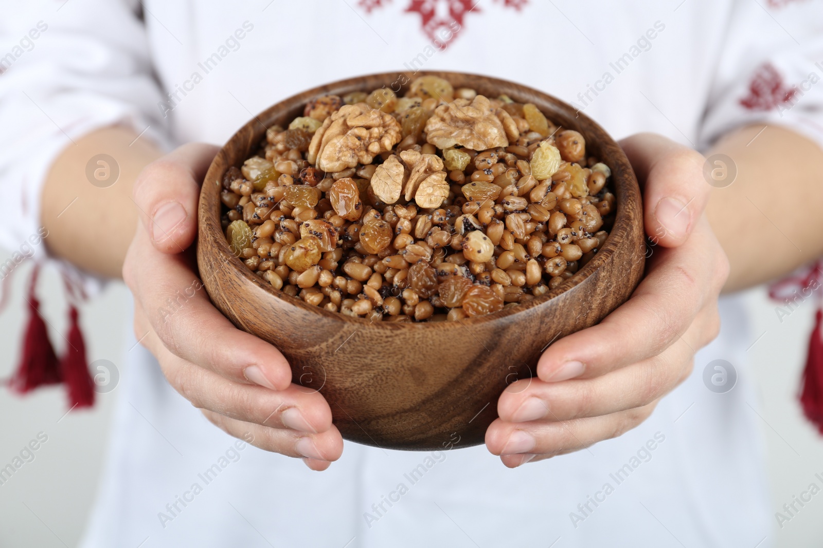 Photo of Woman in slavic shirt holding bowl with traditional kutia, closeup