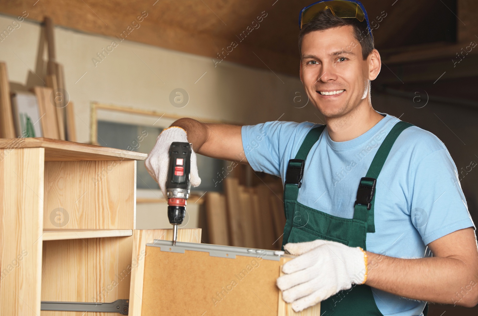 Photo of Professional carpenter twisting screw into wooden drawer in workshop