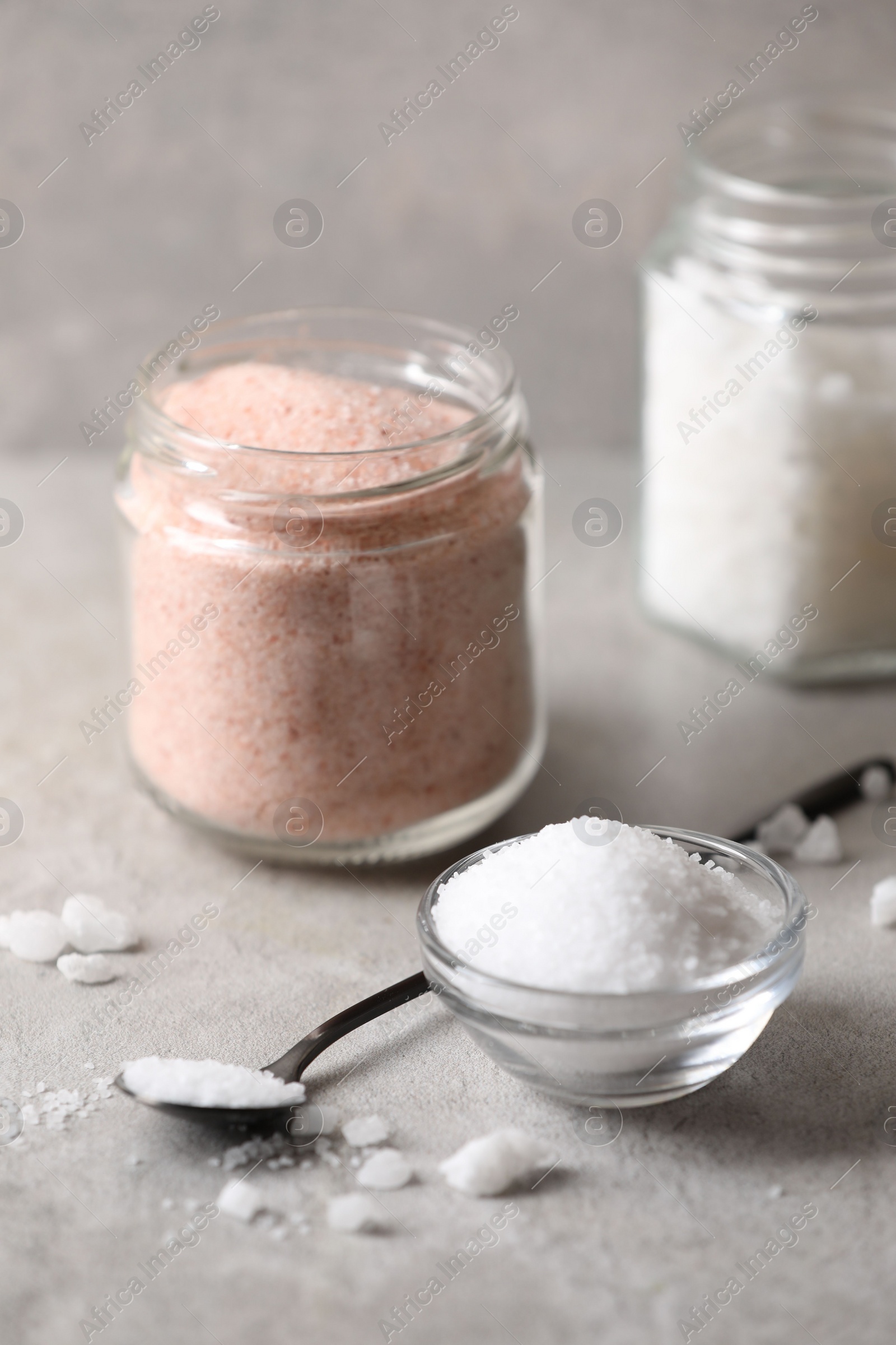 Photo of Different natural salt on grey table, closeup