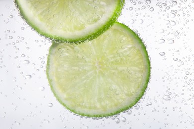 Juicy lime slices in soda water, closeup