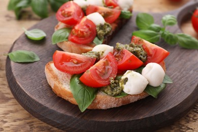 Photo of Delicious Caprese sandwiches with mozzarella, tomatoes, basil and pesto sauce on wooden table, closeup