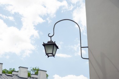 Photo of Vintage street lamp on wall of building against blue sky, low angle view