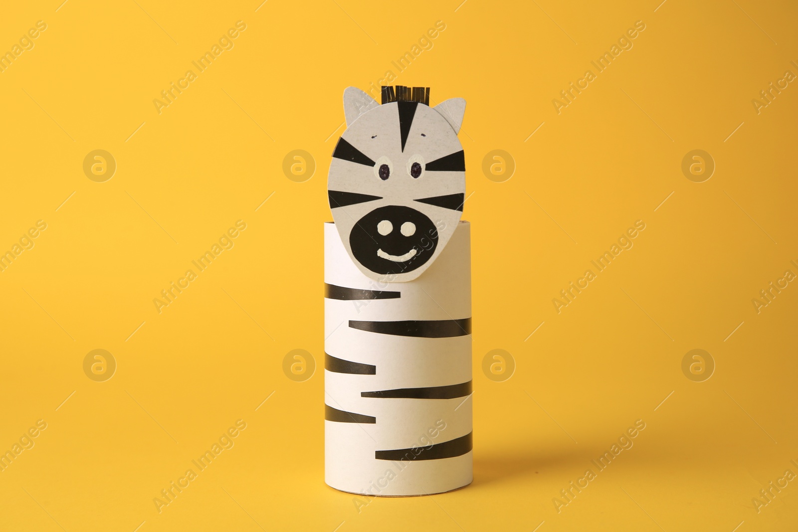 Photo of Toy zebra made from toilet paper hub on yellow background. Children's handmade ideas