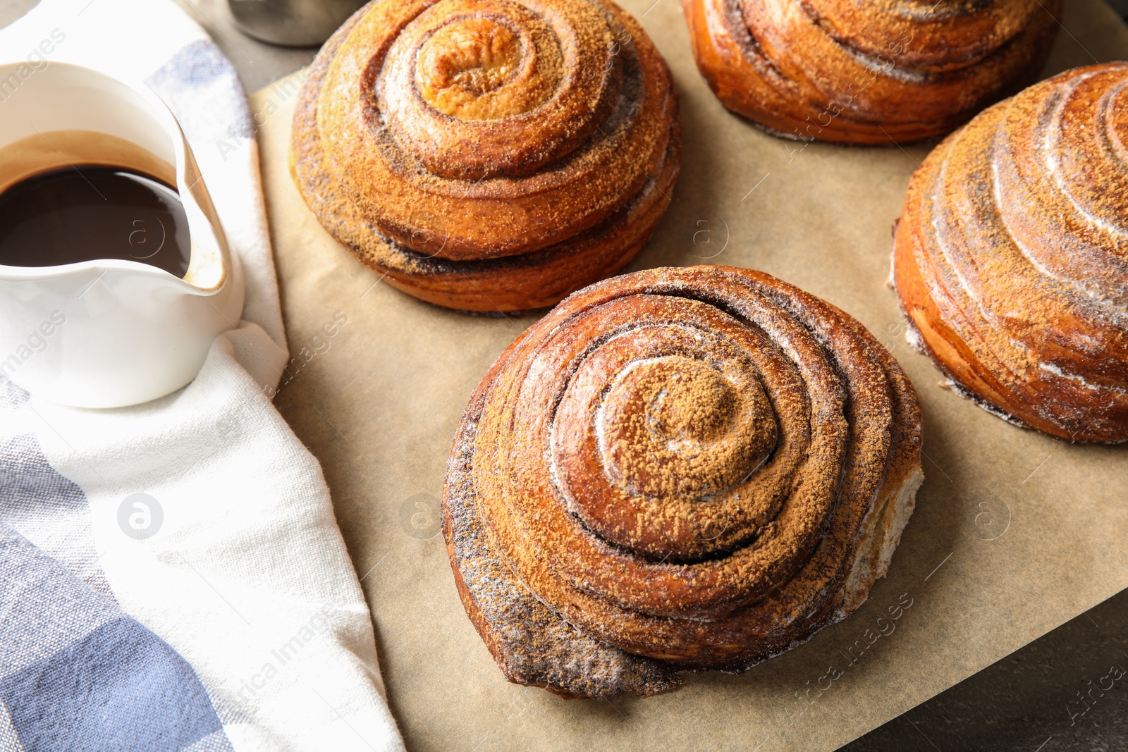 Photo of Cinnamon rolls and jug with chocolate syrup on table