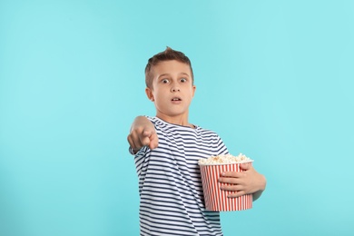 Emotional boy with popcorn during cinema show on color background