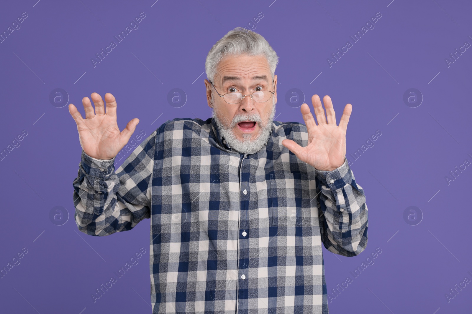 Photo of Portrait of surprised senior man on violet background