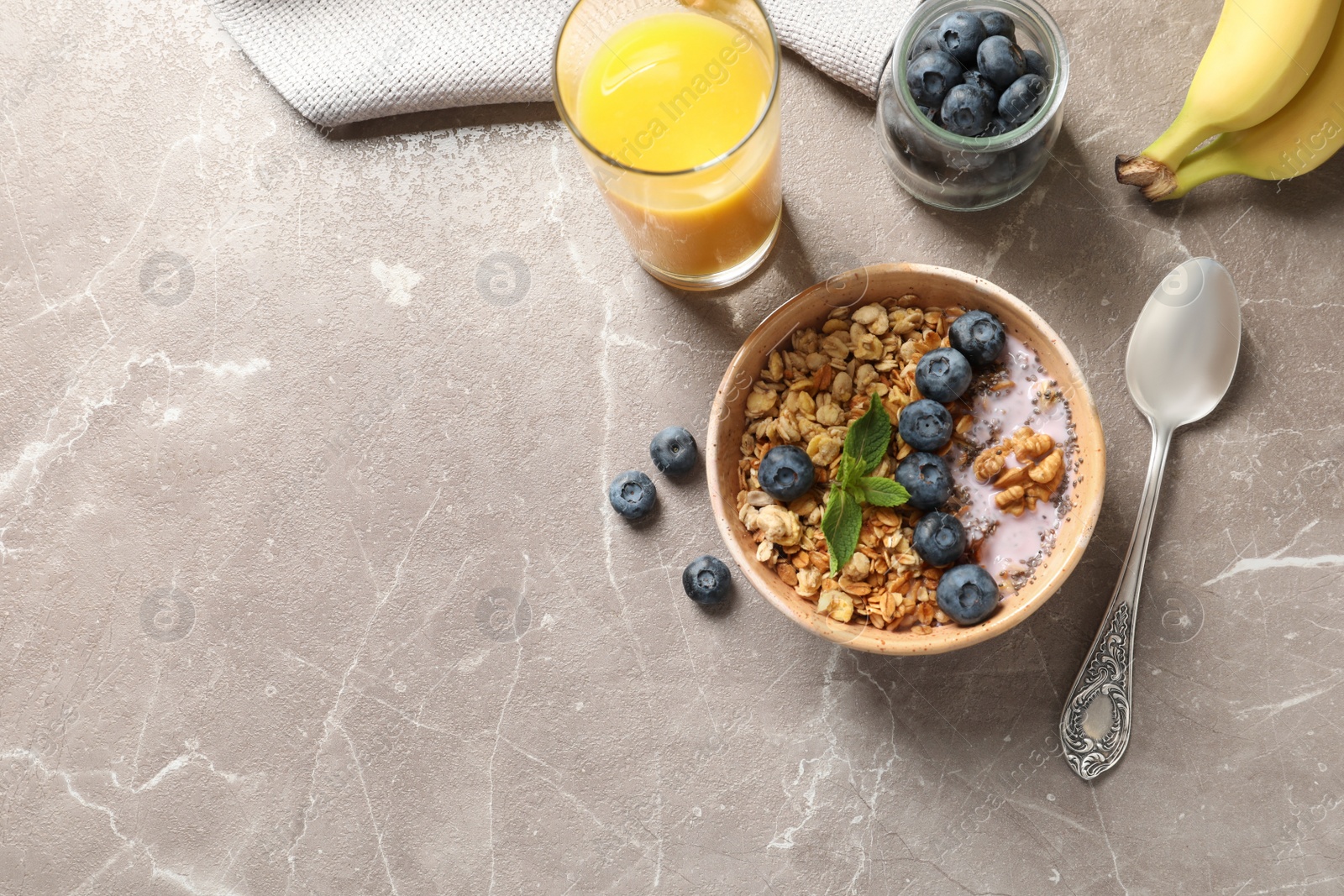 Photo of Bowl of tasty oatmeal with blueberries and yogurt on marble table, flat lay. Space for text