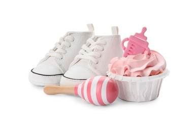 Photo of Baby shower cupcake with pink cream near shoes and toy on white background