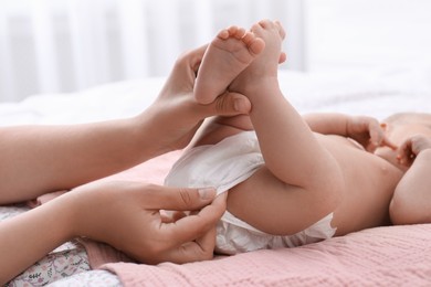 Photo of Mom changing baby's diaper on bed at home, closeup
