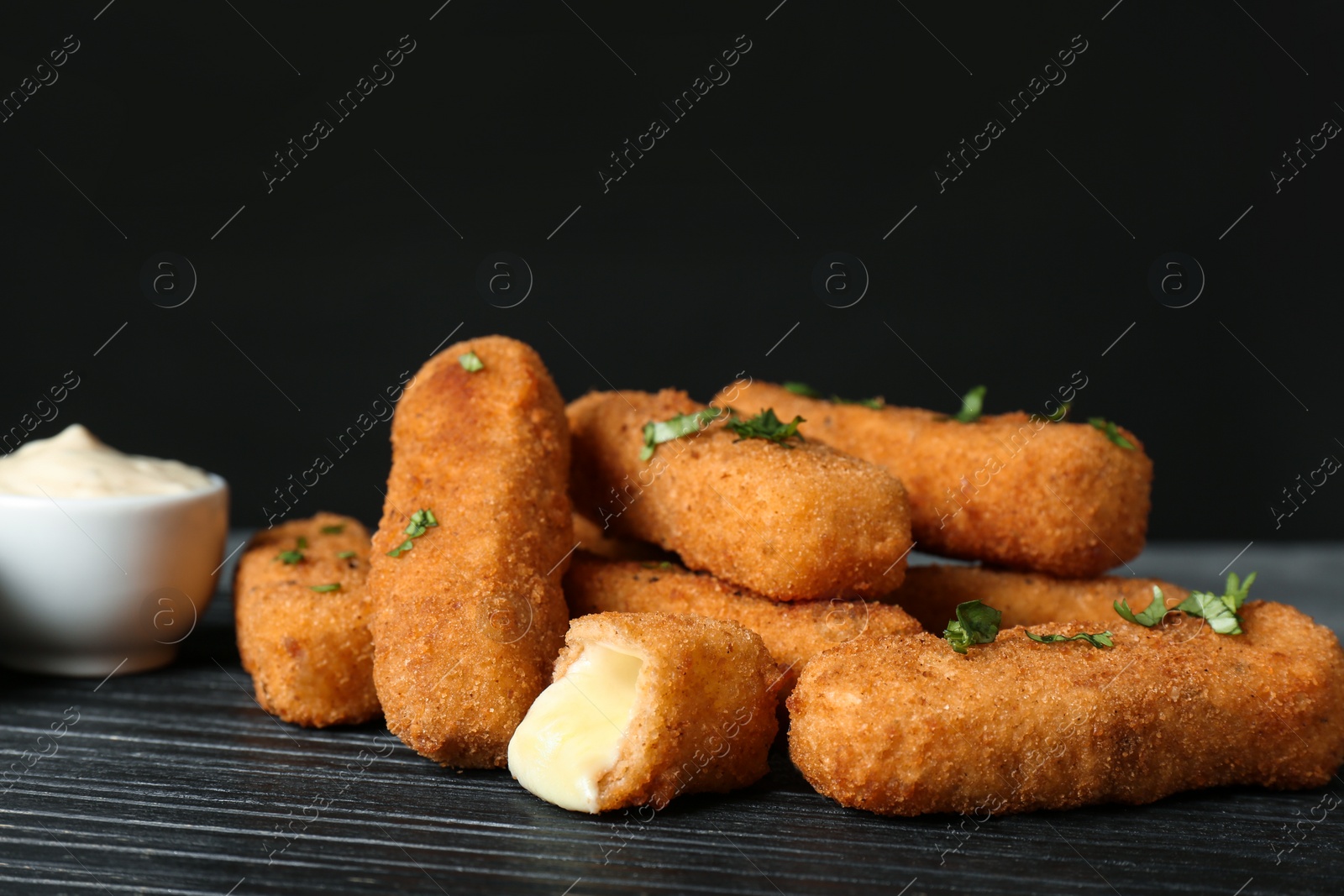 Photo of Pile of tasty cheese sticks and sauce on table, closeup