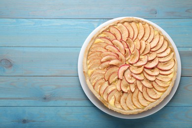 Photo of Tasty apple pie on light blue wooden table, top view. Space for text