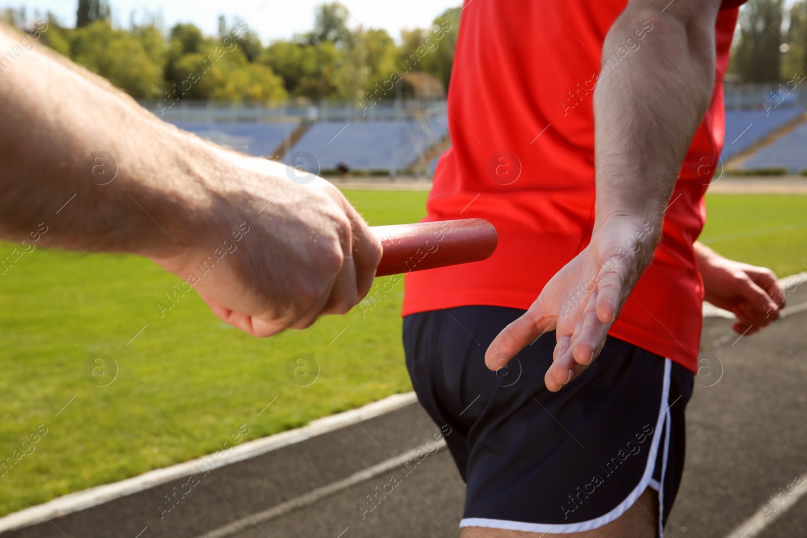 Photo of Man passing baton to his partner at stadium, closeup