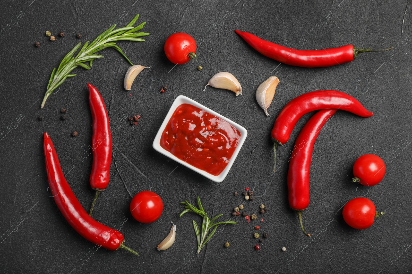 Photo of Flat lay composition with chili sauce and different spices on dark background