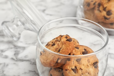 Photo of Jar with chocolate chip cookies on table, closeup