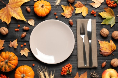Photo of Flat lay composition with tableware, pumpkins and autumn leaves on black wooden background. Thanksgiving Day