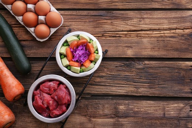 Photo of Flat lay composition with healthy dog food on wooden background. Space for text